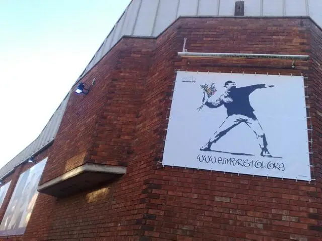 In this image we can see a building, on the building there are few lights and a poster, on the...