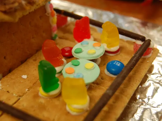 In this image there are jelly's and germs on the cake, around the cake there are chocolate sticks.